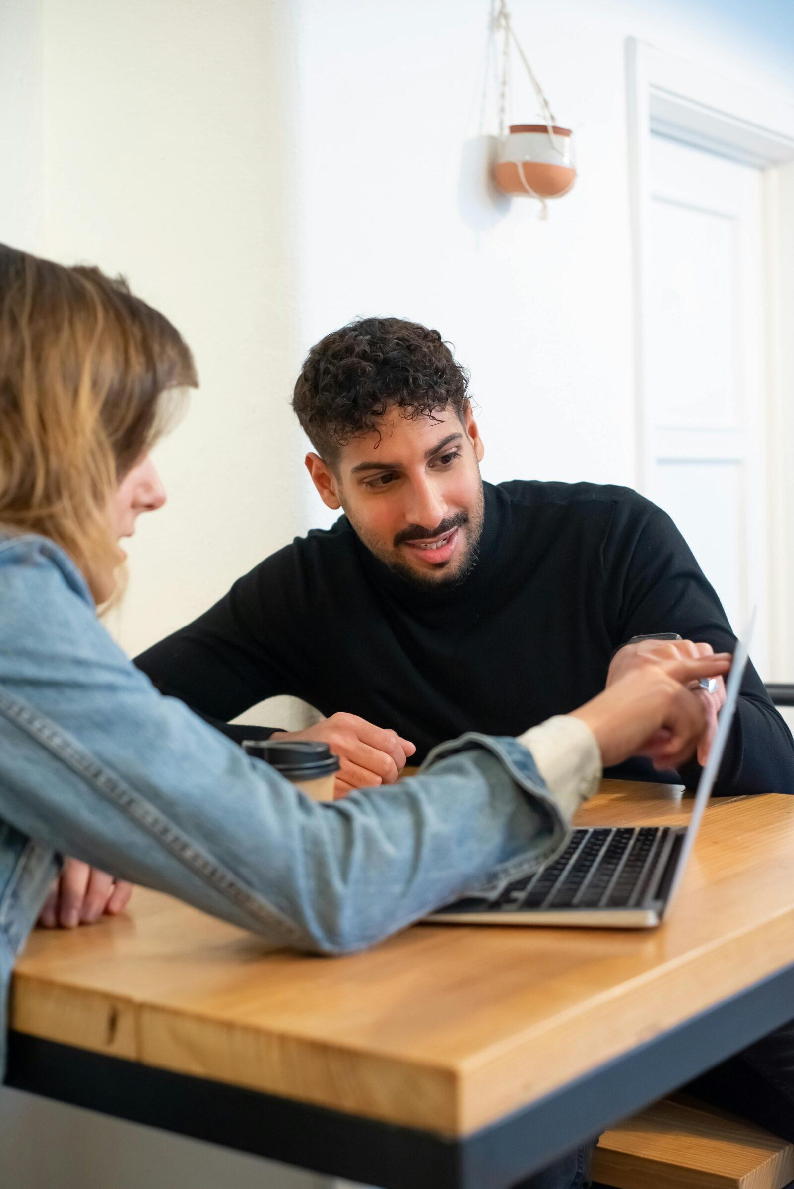 Two people discussing information on a laptop screen.